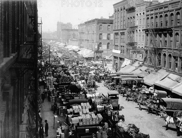 Photograph of horse-drawn wagons and motor trucks