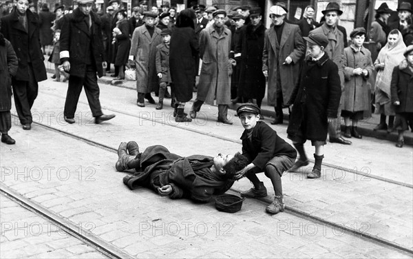 Photograph of a young boy helping a collapsed man.