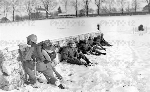 Swiss soldier in the snow peeking over a wall