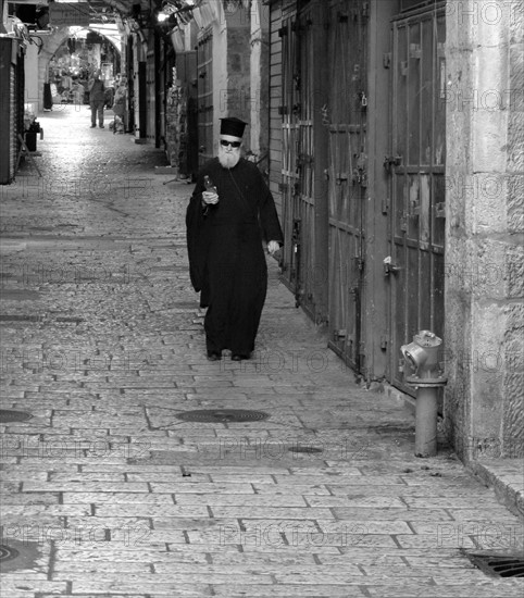 Greek orthodox priest walks through the old city of East Jerusalem; Israel.