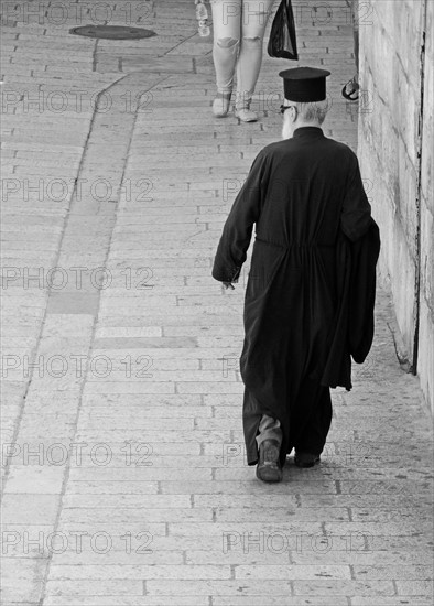 Greek orthodox priest walks through the old city of East Jerusalem; Israel.