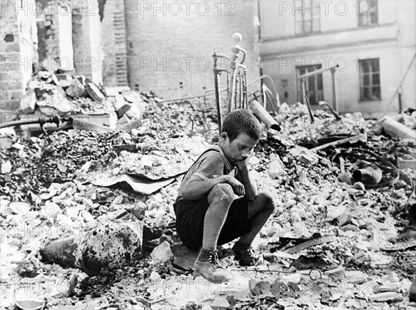 Polish boy sits grieving in the ruins of a street in Warsaw, Poland, September 1939