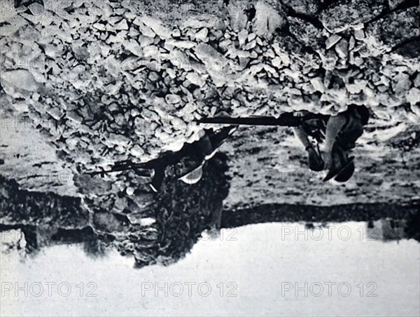 Photograph of British soldiers taking cover behind a destroyed wall