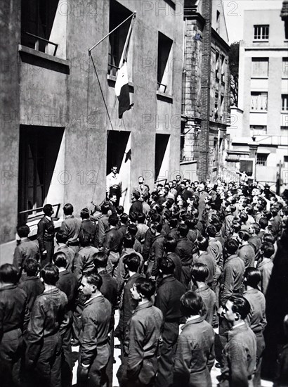 Photograph of young French workmen at a factory listen to news of the German invasion of France 1940