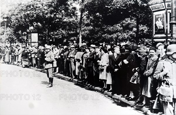 Photograph of crowds gather on the Champs-Élysées in Paris to see German troops enter Paris after the invasion of France in World War Two