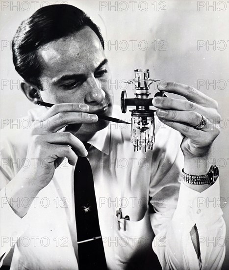 Photograph of a technician holding a laser 'demodulator' used to convert laser light beams into television signals and radio sounds
