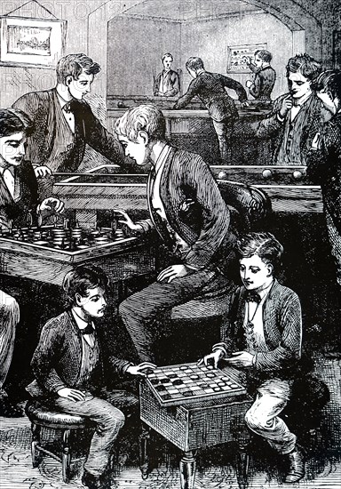 Boys in a games room amusing themselves with, among other things, chess and draughts