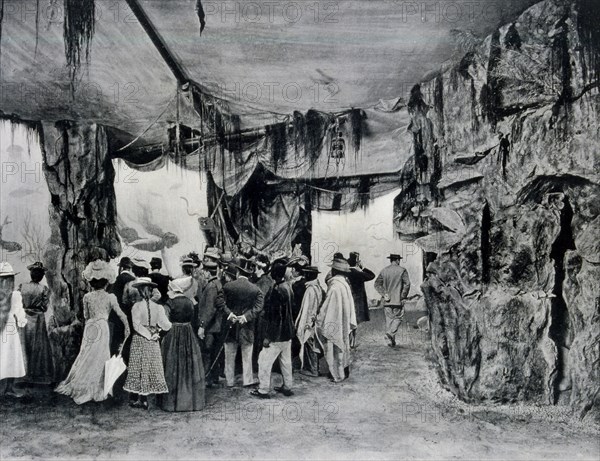 Photograph of visitors of the Exhibition looking through the glass at the Aquarium of Paris.