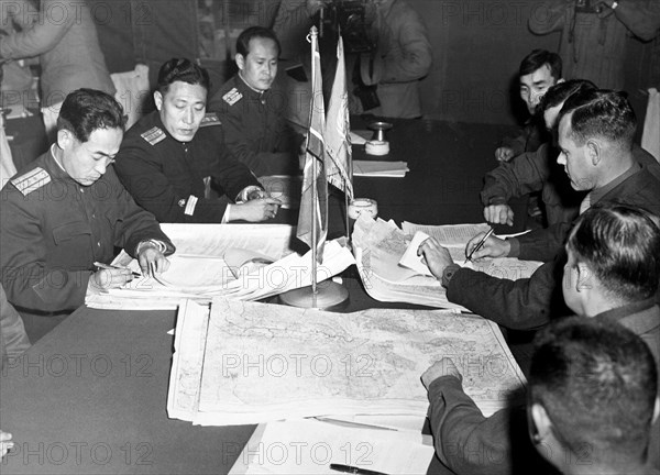 Col. James Murray, Jr., USMC, and Col. Chang Chun San, of the North Korean Communist Army, initial maps showing the north and south boundaries of the demarcation zone, during the Panmunjom cease fire talks