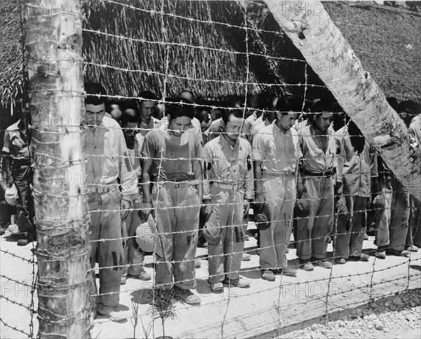 Japanese POW at Guam, with bowed heads after hearing Emperor Hirohito make announcement of Japan's unconditional surrender