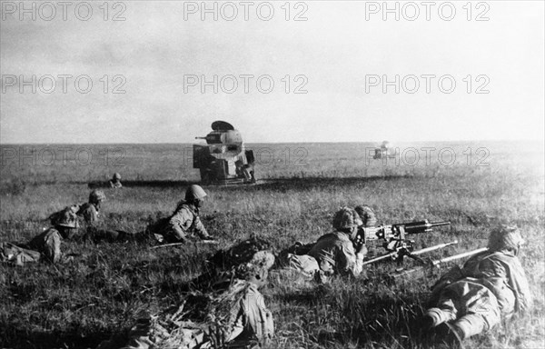 Japanese soldiers creeping in front of wrecked Soviet armored cars in Mongolia during the Battle of Khalkhyn Gol