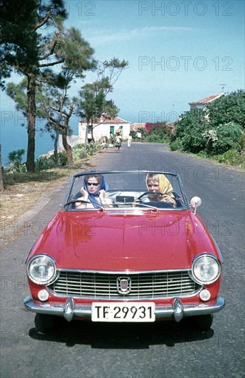 Femmes dans une Fiat rouge 1500 Spider