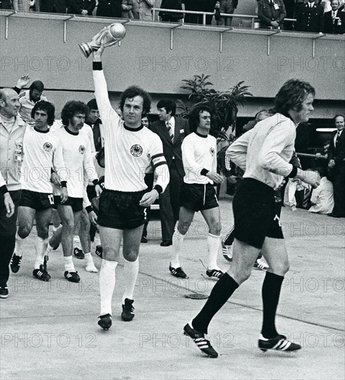 Fussball-Weltmeisterschaft 1974 in Deutschland     Fussball-WM 1974,  Finale in Muenchen, Niederlande - BRD 1:2    - Die BR Deutschland ist Weltmeister. Nach dem Gruppenfoto der deutschen Nationalmannschaft nach der Siegerehrung verlassen die Nationalspieler den Platz vor der Ehrentribuene. Vorne Franz Beckenbauer mit WM-Pokal, rechts laeuft Torwart Sepp Maier aus dem Bild.   -   - 07.07.1974            <english> 1974 FIFA World Cup in Germany    Final in Munich:  Germany 2 - 1 Netherlands  - Germany player Franz Beckenbauer raising the World Cup trophy| right: goalie Sepp Maier   -   - 07.07.1974             </english>