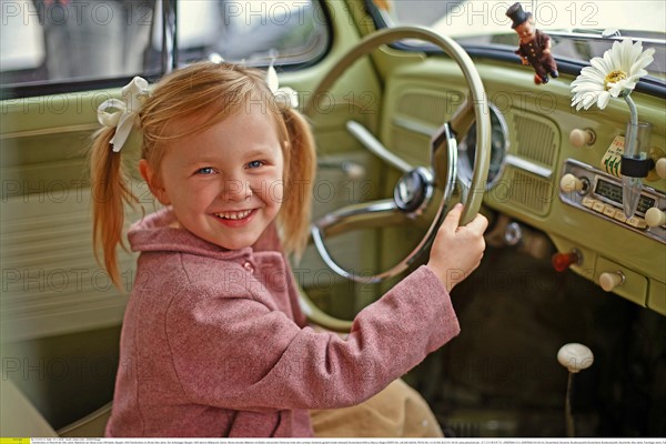 : Familienfotos im Retrostil der 50er Jahre, Maedchen am Steuer eines VW Kaefer, Baujahr 1955