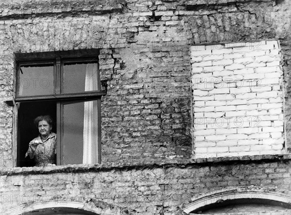 Germany / GDR, Berlin. The building of the wall. A woman in a house in East-Berlin looking out of a window. 1961