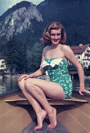 Young woman in a bathing suit sits on a rowing boat