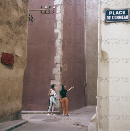 In the 1960s. Two female tourists in a street corner in the town Saint-Tropez on the French riviera. T...