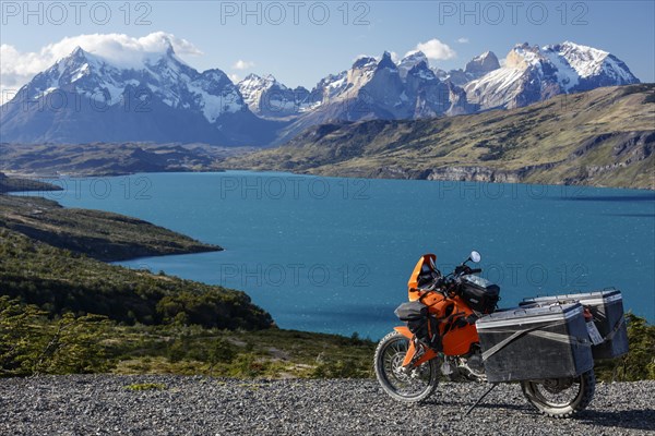 A heavily packed motorcycle on a gravel road behind the Lago del Torro and the mountain group Cordillera Paine