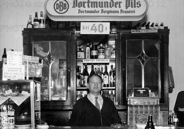 Innkeeper stands behind the bar of a pub