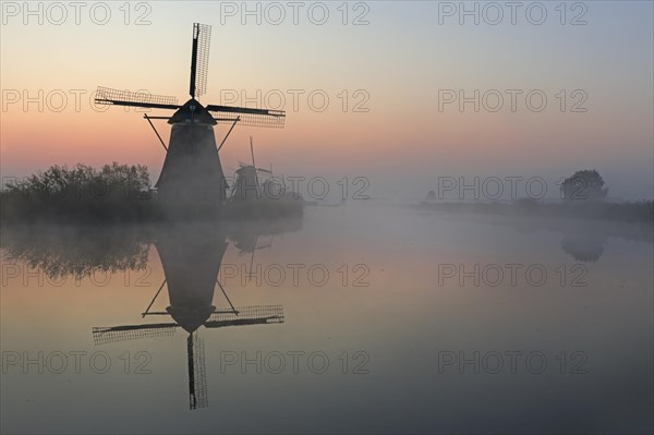 Historical windmills in the early morning fog at dawn