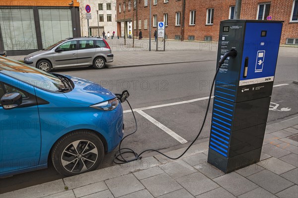 Electric car is charged at green electricity charging station with charging cable