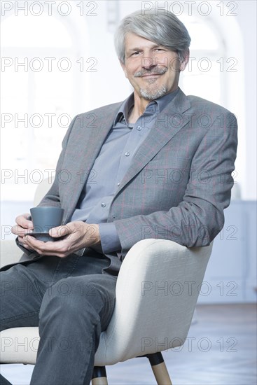 Man sits in his office chair with a coffee cup