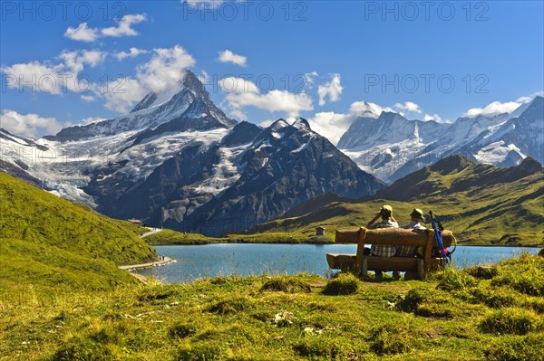 Hikers pausing on a wooden bench at lake Bachalpsee