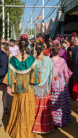 Spanish women with colorful flamenco dresses in front of marquees