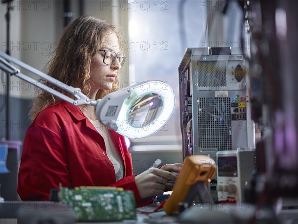 Technician measures with a measuring device in an electronics laboratory