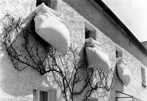 Bedding hanging from three windows for airing
