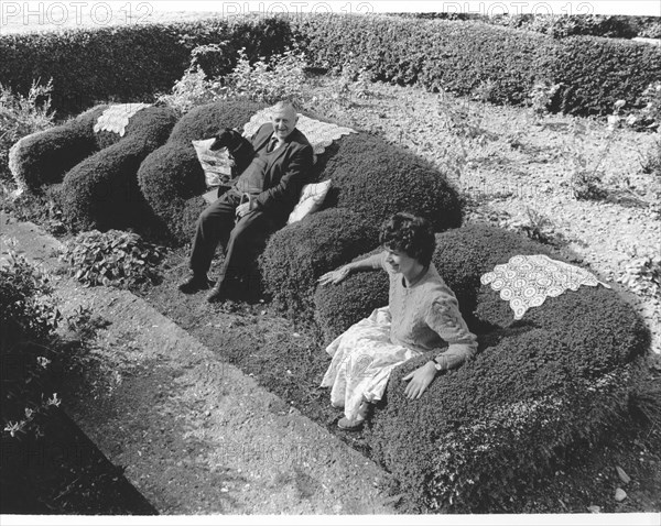 Old couple sitting on an armchair from a hedge