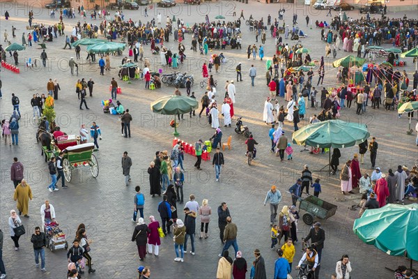 Crowds of people walk across Jamaa El-Fna square