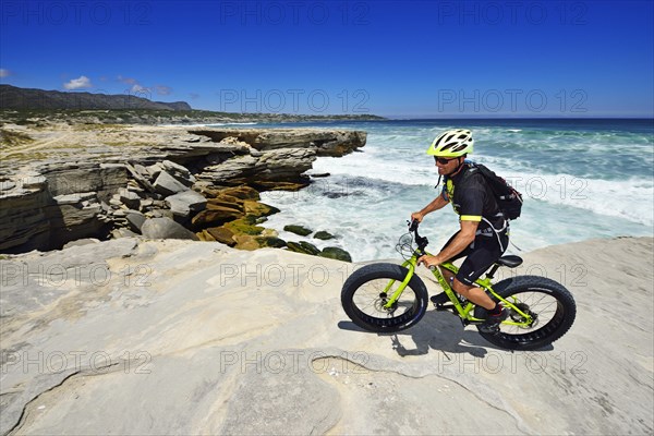Mountain biker with Fatbike on cliff