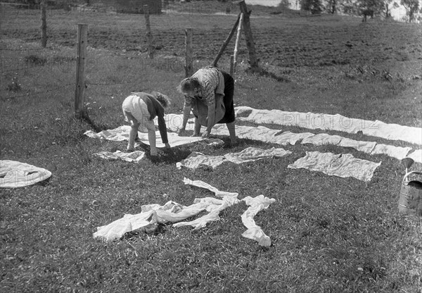 Mother and child put the laundry on the lawn and in the sun