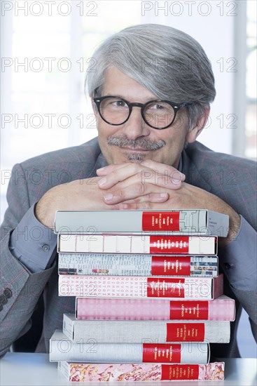 Man leaning on a book pile