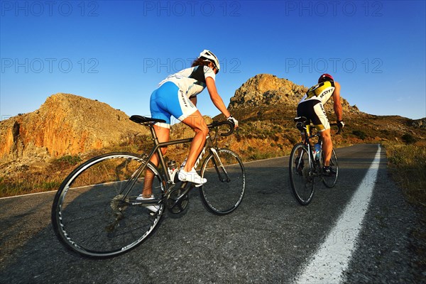 Two racing cyclists cycle uphill on the road