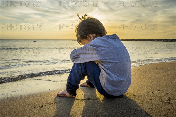 Sad boy sitting on the beach