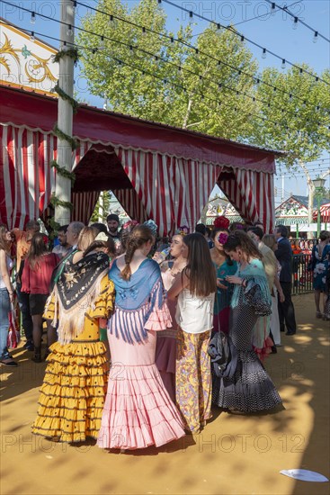 Spanish women with colorful flamenco dresses in front of marquees