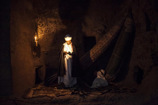 Coptic priest by candlelight in Rock Church