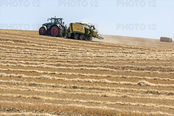 Tractor with straw baler on a mown wheat field