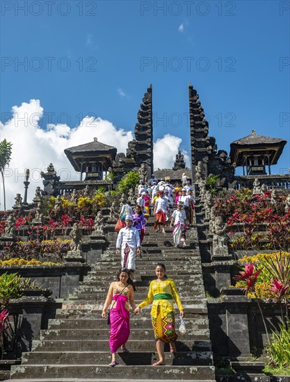 Balinese believers in traditional clothing go down stairs