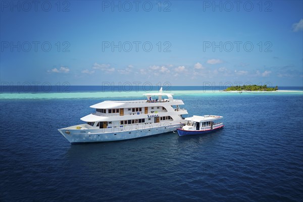 Diving safari ship MS Keana with diving dhoni anchored off an uninhabited palm island