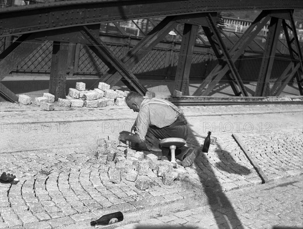 Road worker paving a road with natural stones