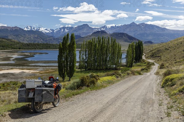 Heavily packed motorcycle on a gravel road in front of a lake