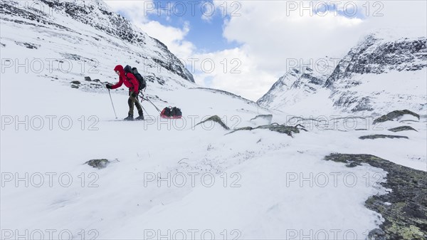 Ski tourer with pulka in the snow