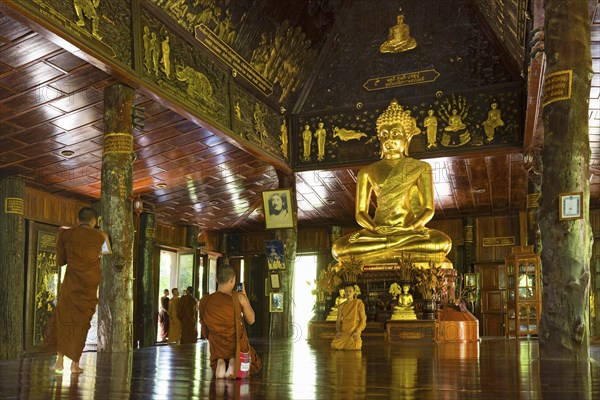 Monks in front of golden Buddha statue