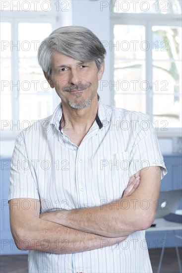 Man standing in his office with his arms crossed