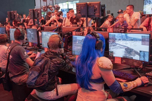 Female visitor in cosplay costume sitting in front of a military computer game