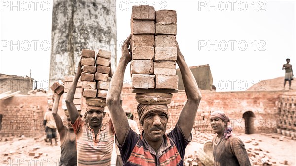 Workers with bricks on their heads in the brickyard