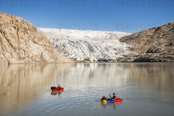 Two persons with pack rafts on fjord